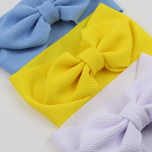 Detailed close-up of textured waffle fabric baby headbands with large bows in three colors