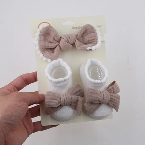 Nahaufnahme von Baby-Stirnband und Socken-Set mit brauner Schleife auf Display-Karte