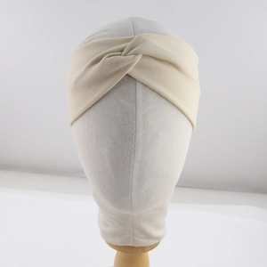 Close-up of beige knitted twist headband for kids with soft cross knot texture