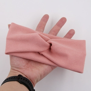 Detail shot of a soft pink twisted knit headband for babies showing texture and elasticity