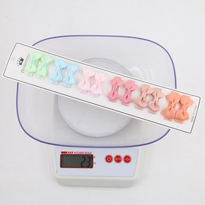 Set of 12 colorful grosgrain ribbon bow hair clips for girls weighed on a digital scale