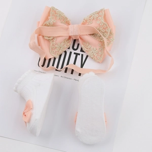 Vue détaillée du bandeau en dentelle rose et chaussettes en coton blanc à rubans