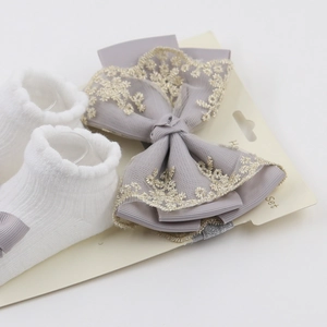 Détail du bandeau à nœud en dentelle et chaussettes blanches avec broderie violette