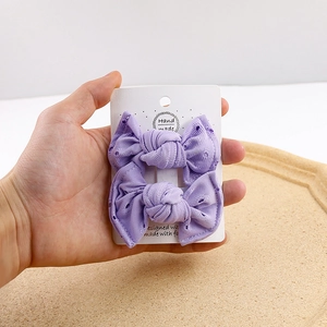Detail of purple lace bow hair clips with delicate eyelet embroidery and ribbed fabric texture