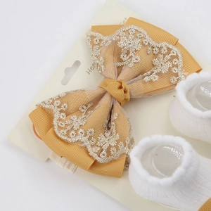 Vue détaillée du bandeau en dentelle gingembre et des chaussettes blanches pour bébés
