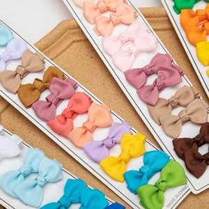 Primer plano de lazos de colores en cinta de grosgrain sobre cartón y fondo de madera