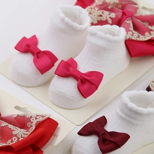 Détail de chaussettes bébé et bandeaux en dentelle avec nœuds rouges festifs