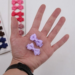 Macro detail of various colorful ribbon bow hair clips held to show small size