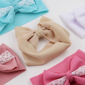 Set of five colorful baby headbands with large lace-trimmed bows on textured fabric