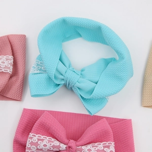 Detailed macro view of infant headbands with lace flower embroidery on ribbed fabric bows