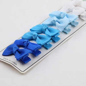 Detalle de cuatro pares de pinzas para el pelo con lazos azules degradados en tarjeta