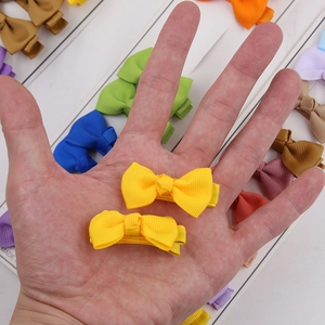 Detalle de mini pinzas de lazo de colores en faya con textura hecha a mano y tamaño pequeño