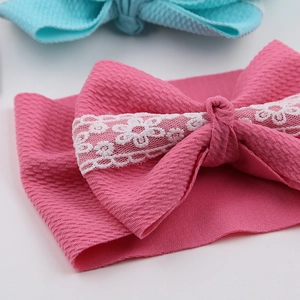 Detail of rose red ribbed baby headband with large bow and white floral lace detail