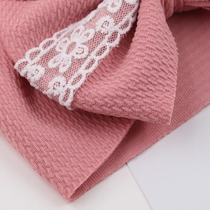 Close-up of pink textured bubble fabric and delicate white floral lace on baby headband