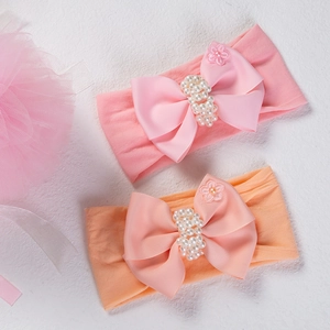 Détail de bandeaux bébé en nylon avec grands nœuds, perles et fleurs décoratives