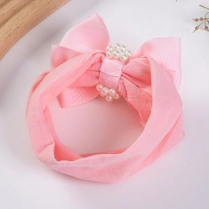 Détail d'un bandeau rose pour bébé avec nœud, perles et tissu en nylon doux et souple