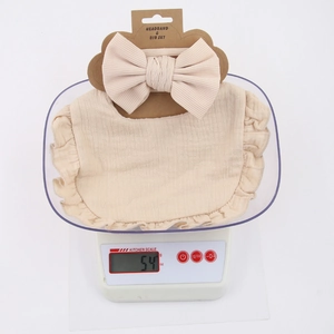 Cotton muslin baby bib and bow headband set in beige with ruffled edges, weighing 54g