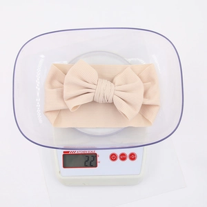 Detailed view of lightweight 22g cotton baby headband with bow on a kitchen scale