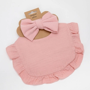 Detailed view of pink ruffle gauze bib and ribbed bow headband on display card
