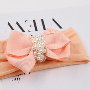 Gros plan sur un bandeau en nylon pêche avec nœud côtelé, perles et petite fleur