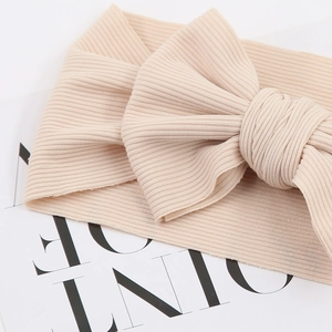 Detailed close-up of ribbed cotton baby headband with a large beige bow on card