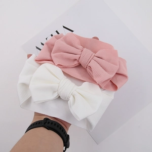 Detailed view of pink and white ribbed knit baby headbands with large bows