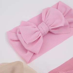 Close-up of baby ribbed cotton headband featuring a large soft pink bow and fabric texture