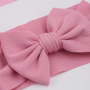 Close-up of pink ribbed knit texture and large bow detail on baby headband