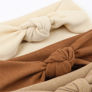 Detail of three ribbed knit baby headbands in beige, dark brown, and khaki earth tones