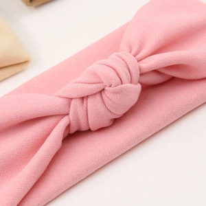 Detail shot of light pink ribbed knit baby headband with a stylish central knot design