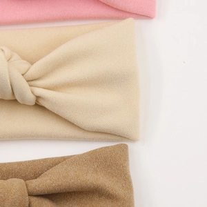Detail of soft ribbed fabric textures on baby bow headbands in pink, beige, and brown