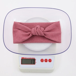 Detailed view of pink lace baby headband showing lightweight 17g weight on kitchen scale