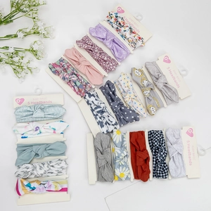 Close-up of five baby headbands with assorted floral and bow patterns in soft fabric