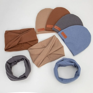 Flat lay of knit infant beanies, headbands and scarves with handmade leather labels