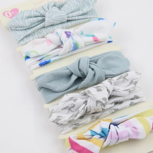 Close-up of five baby bow headbands with floral and stripe patterns on a display card