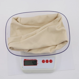 Detailed view of the 40g lightweight beige thermal baby winter hat on a kitchen scale