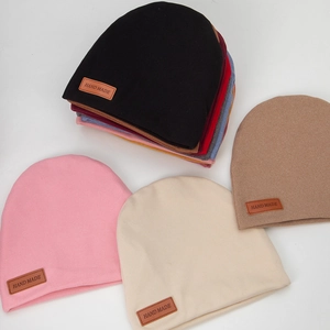 Detailed view of handmade labels on multi-color knitted beanies for infants and toddlers