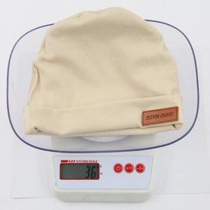 Beige baby cashmere-like knit beanie showing its lightweight design weighing 36 grams