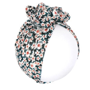 Détail d'un turban en coton pour bébé avec imprimé floral et triple nœud décoratif papillon