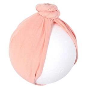 Detail of soft peach cotton baby turban hat showing textured knit and twisted knot