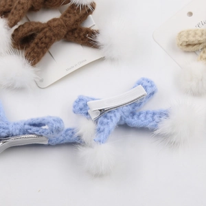 Vue détaillée des pinces à cheveux en coton tricoté main avec pompons en fourrure et clips métal