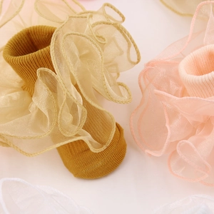 Détail de volants en dentelle d'organza sur des chaussettes en coton rose, blanc et ocre