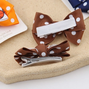 Detailed view of basketball bow hair clips featuring polka dots and metal alligator grips