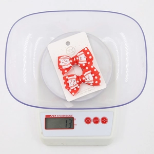 Close-up of baseball pattern hair bows on a scale weighing 13g with a white background
