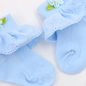 Detail der hellblauen Babysocke mit zartem Spitzenbesatz und dekorativer 3D-Stoffblume
