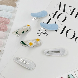 Close-up of embroidered snap hair clips with daisy patterns and soft felt backing