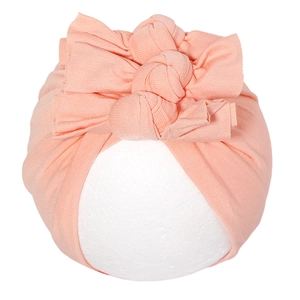 Détail du bonnet rose corail pour nouveau-né avec trois nœuds papillon superposés