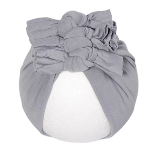 Détail d'un turban gris pour bébé avec trois nœuds sur un support d'exposition