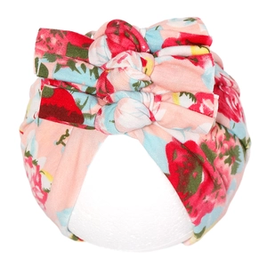 Détail du turban bébé avec trois nœuds et imprimé floral fraise sur tissu rose doux