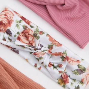 Detaillierte Nahaufnahme weicher Baby-Stirnbänder mit Blumenbogen und rosa Gummibändern